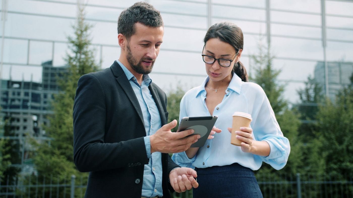 Two professionals reviewing project results on a tablet outdoors